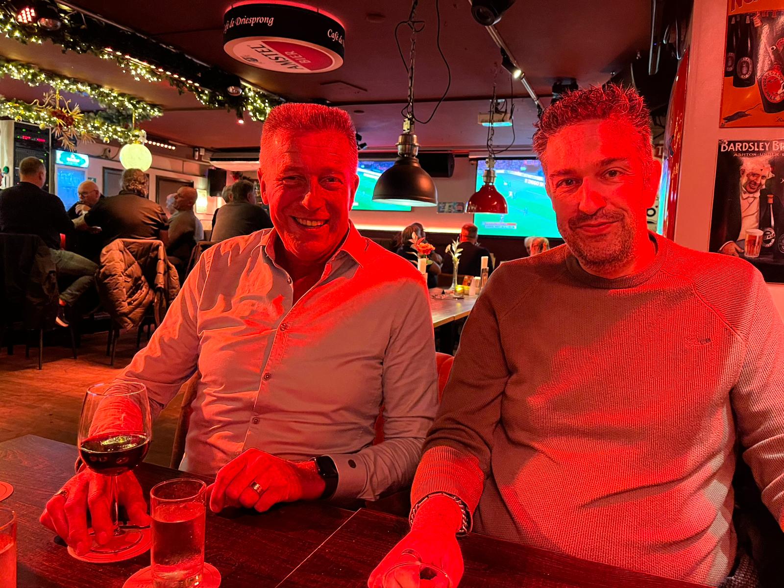 Michel (left) and me sitting at a table in a restaurant under red lighting